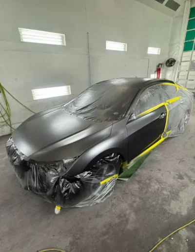 A full vehicle (Tesla_Sedan) in a premium Satin Black_Grey finish in the booth 1