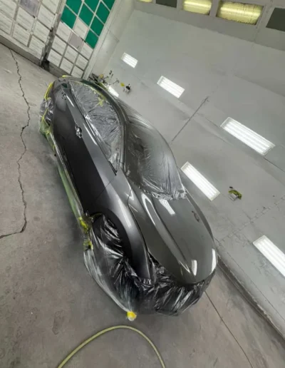 A full vehicle (Tesla_Sedan) in a premium Satin Black_Grey finish in the booth 2