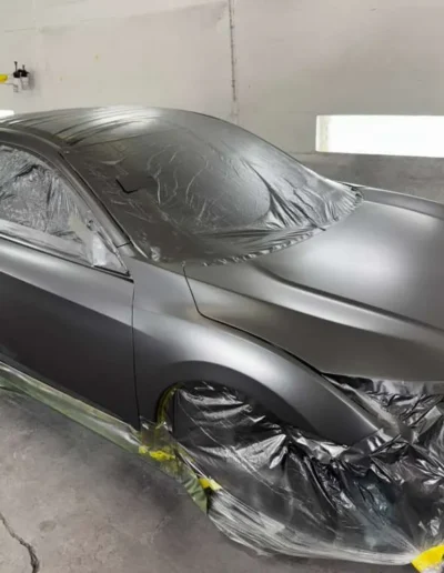 A full vehicle (Tesla_Sedan) in a premium Satin Black_Grey finish in the booth